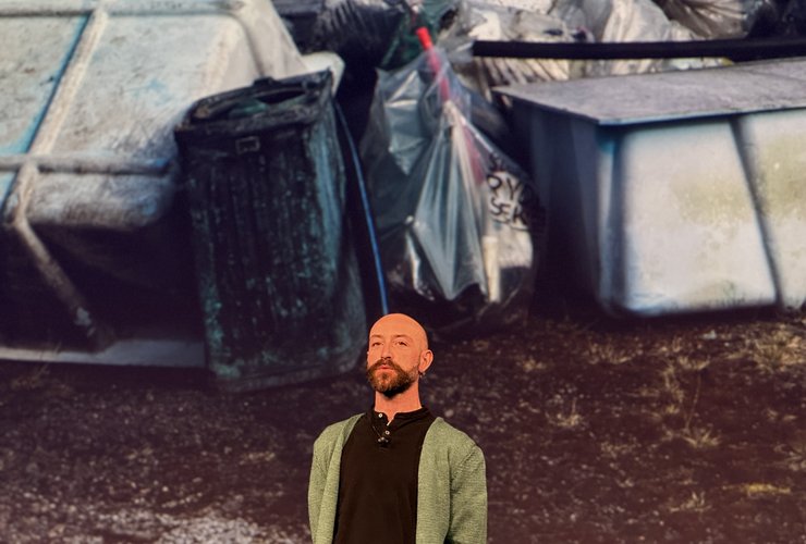 A speaker presenting in front of a photo of washed-up plastic waste during the Day 2 sessions