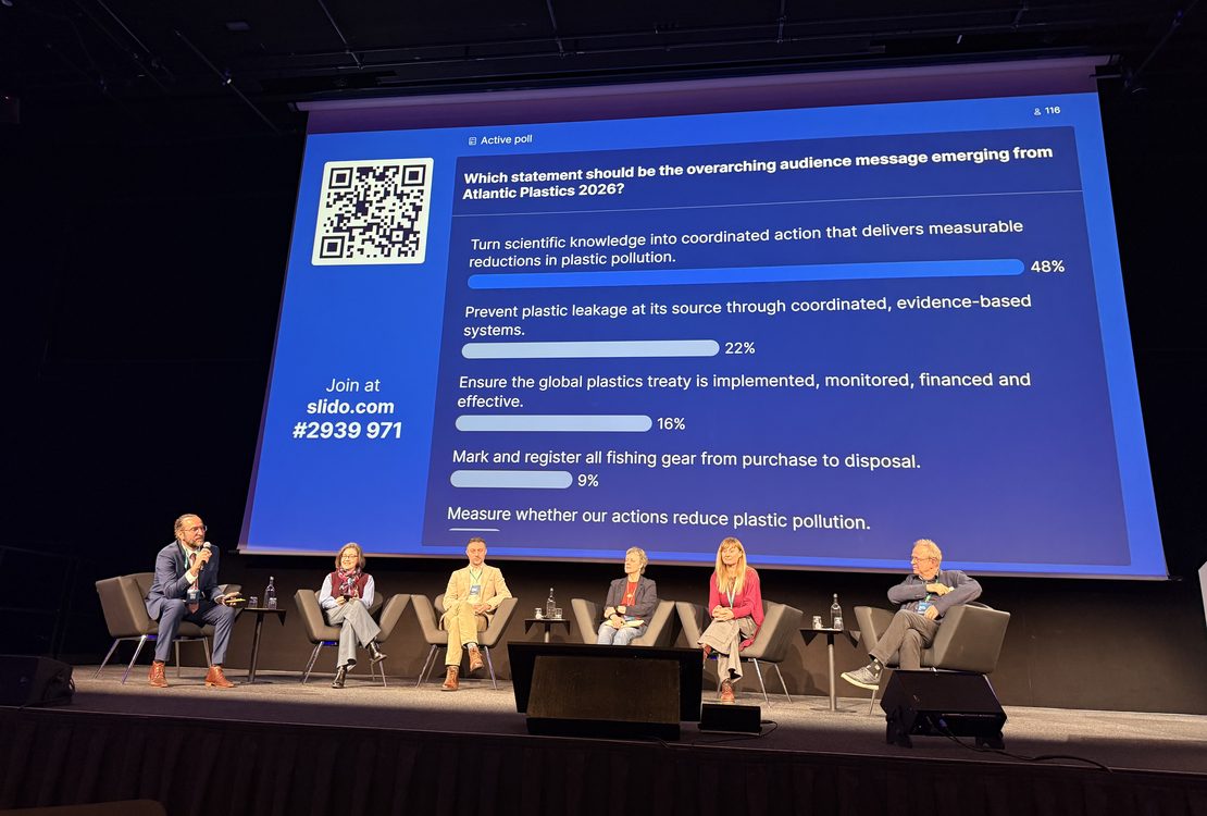 Panellists on stage in front of live survey results during the From Knowledge to Action discussion